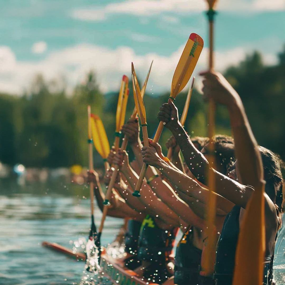 A team of rowers raising their paddles in unison